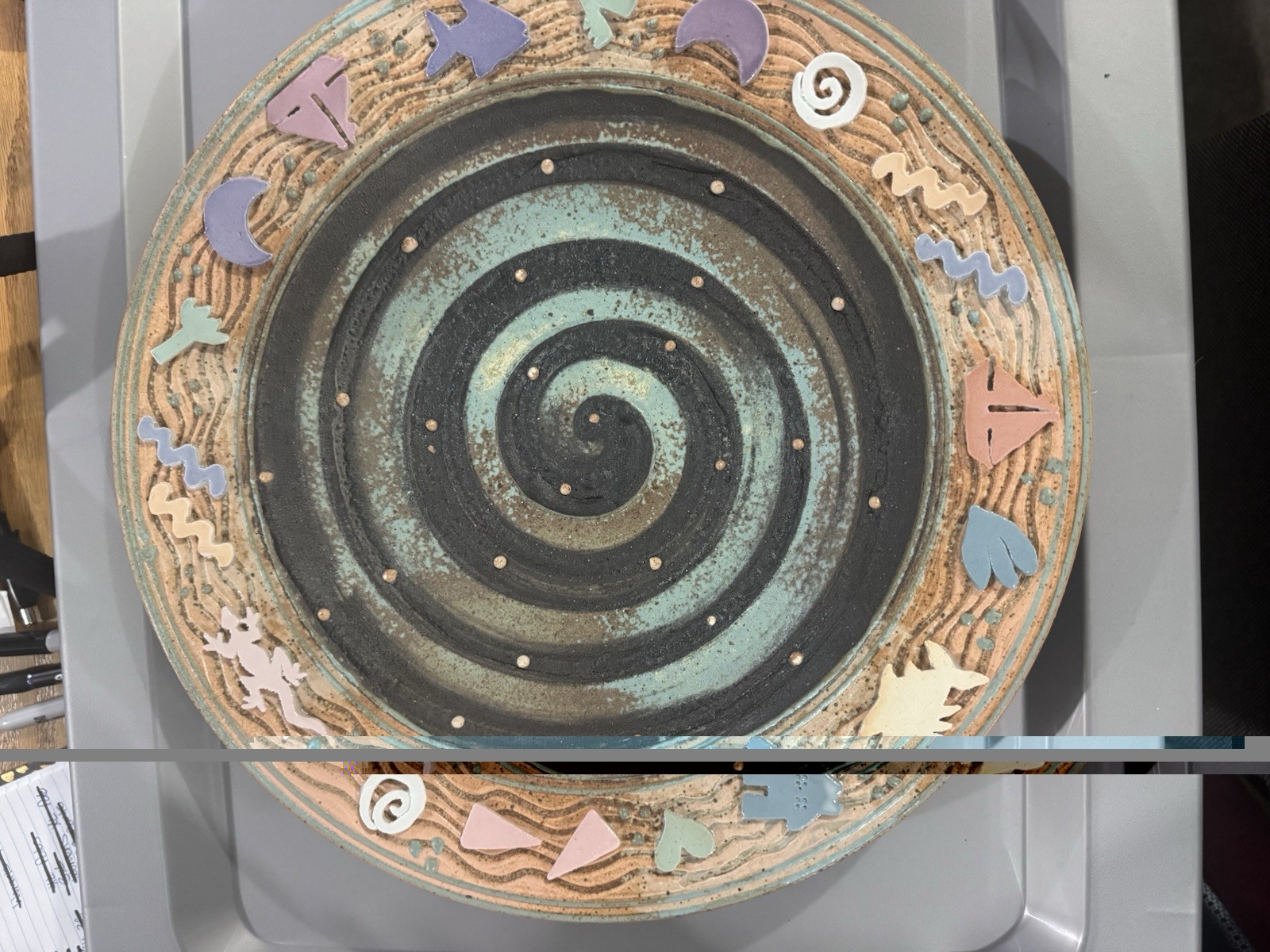 handmade ceramic platter featuring a central spiral design and decorative border