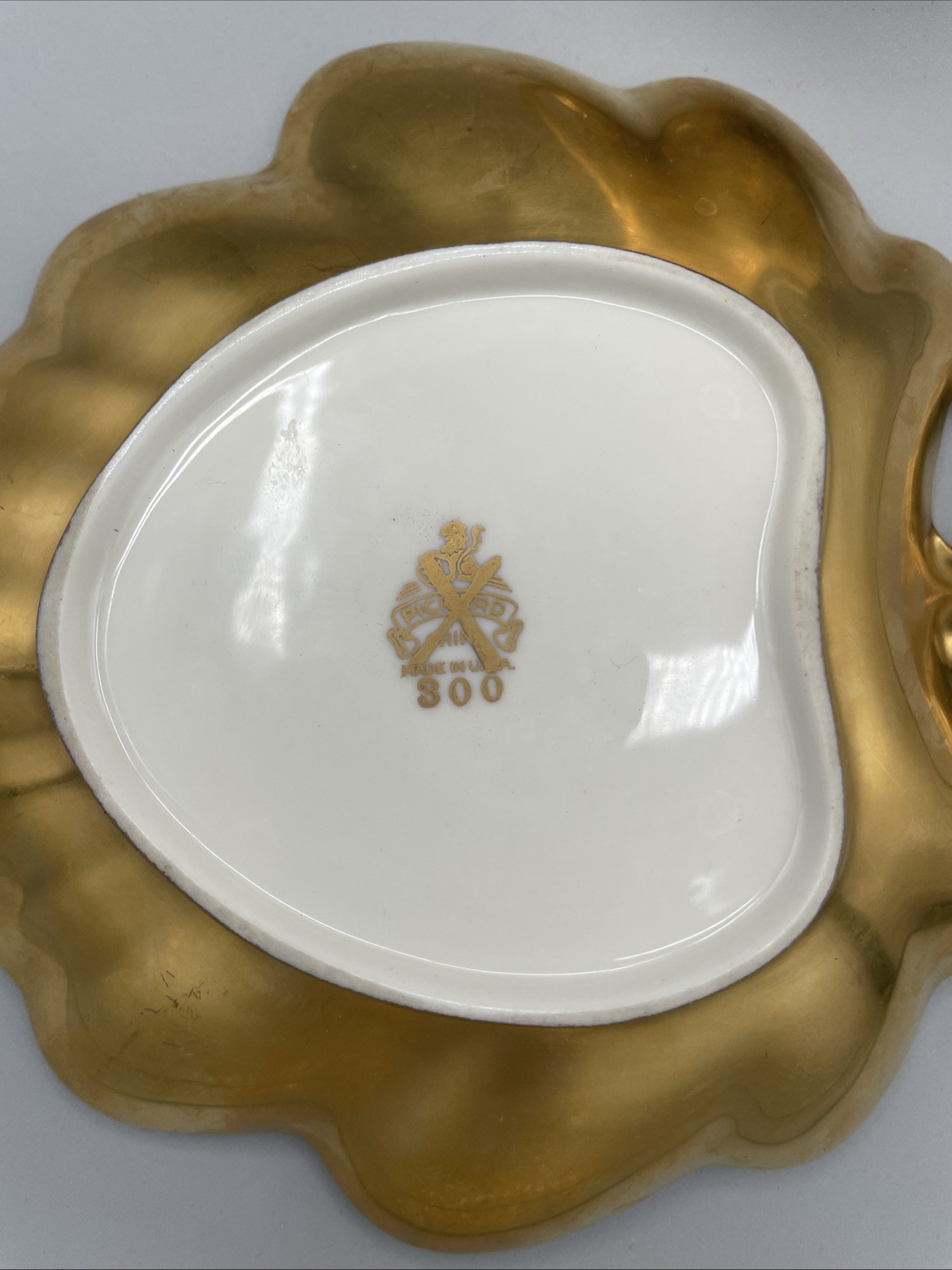 Gilded porcelain creamer and saucer set, from Pickard China.