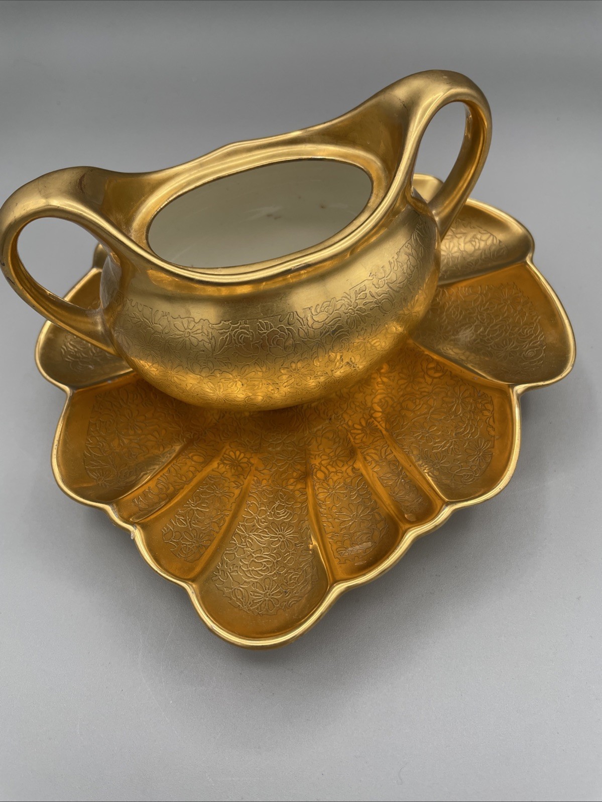 Gilded porcelain creamer and saucer set, from Pickard China.