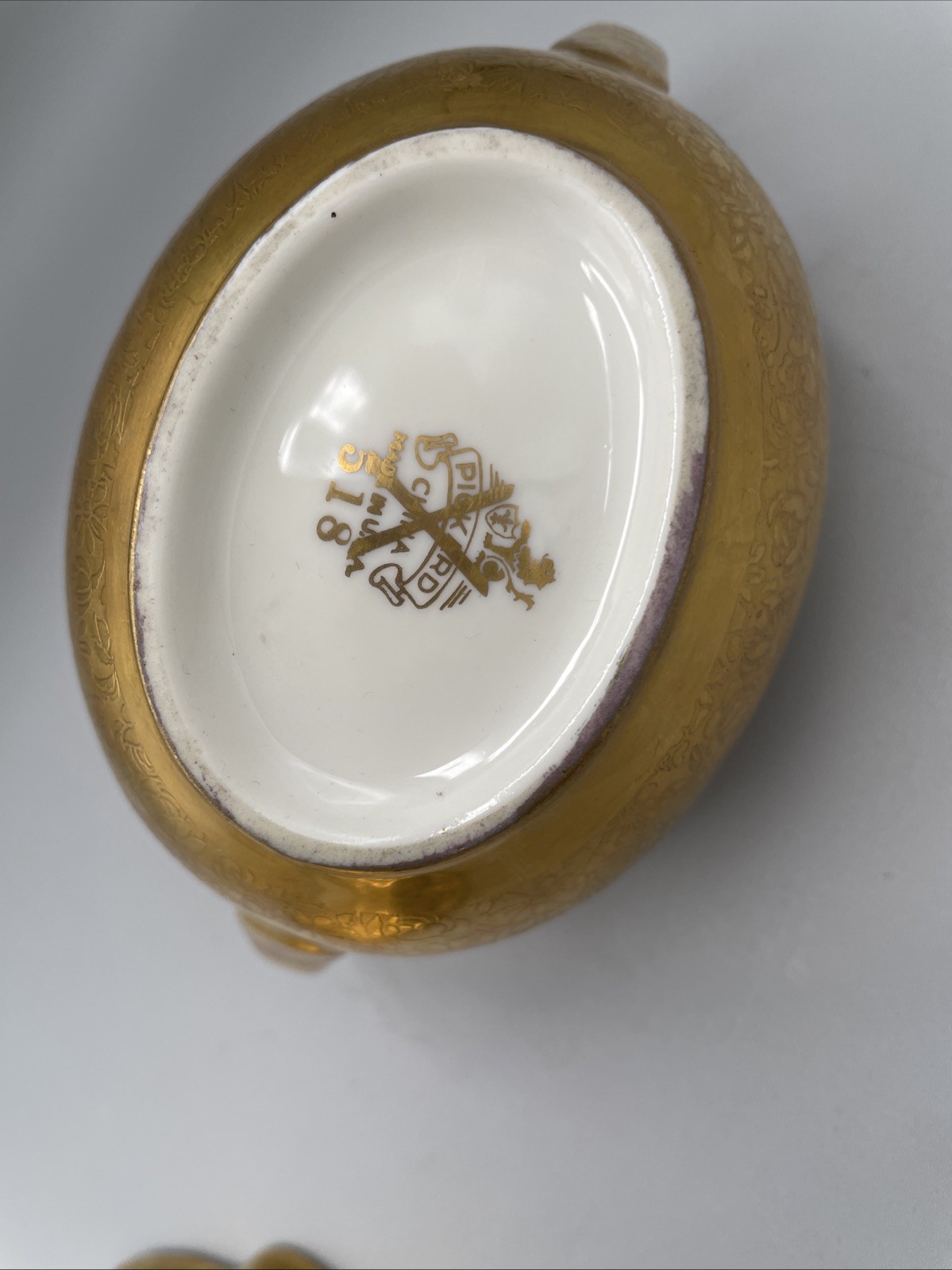 Gilded porcelain creamer and saucer set, from Pickard China.