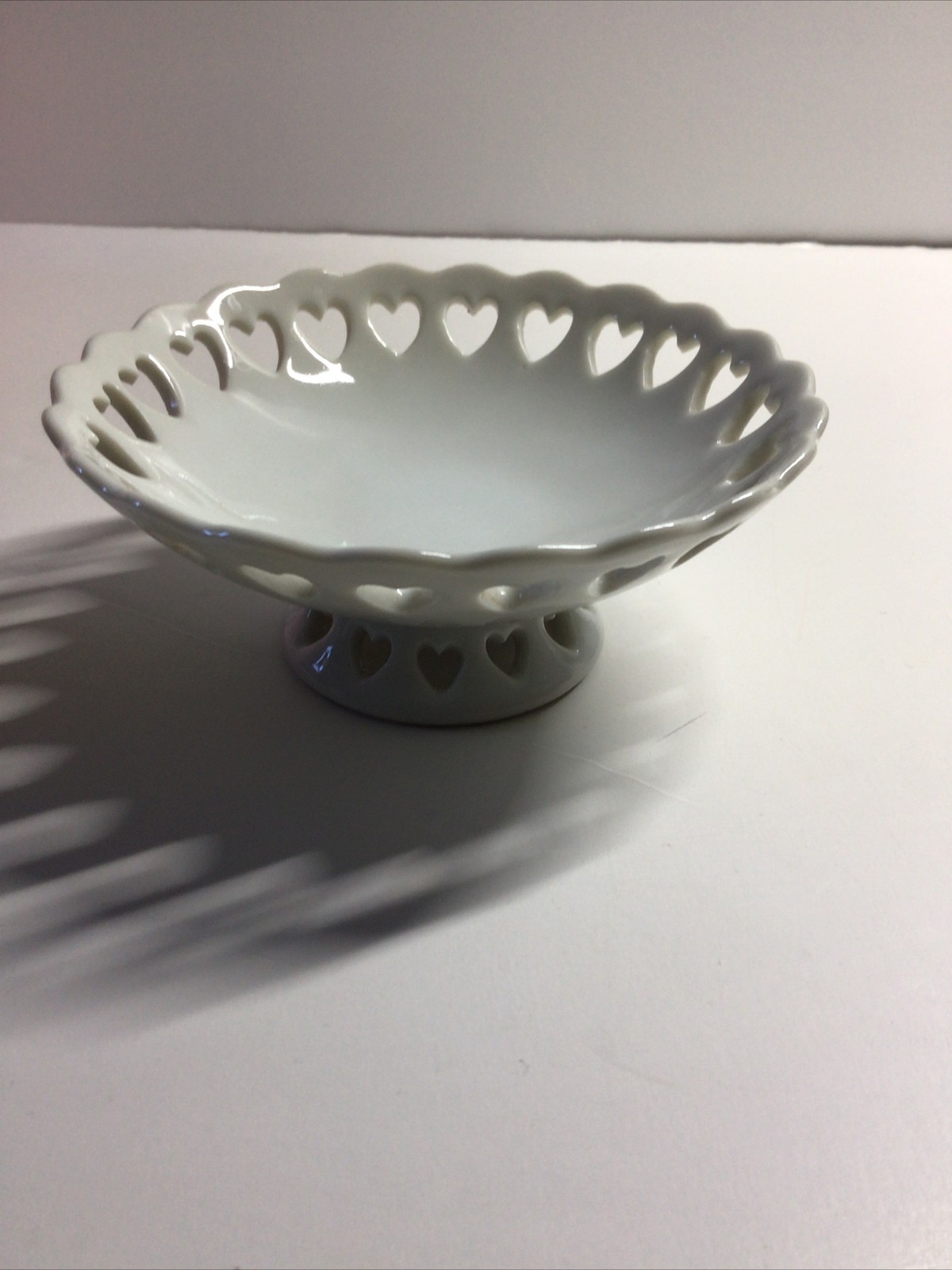 Small White Pedestal Bowl Featuring Cut Out Hearts Around the Top Edge and Base