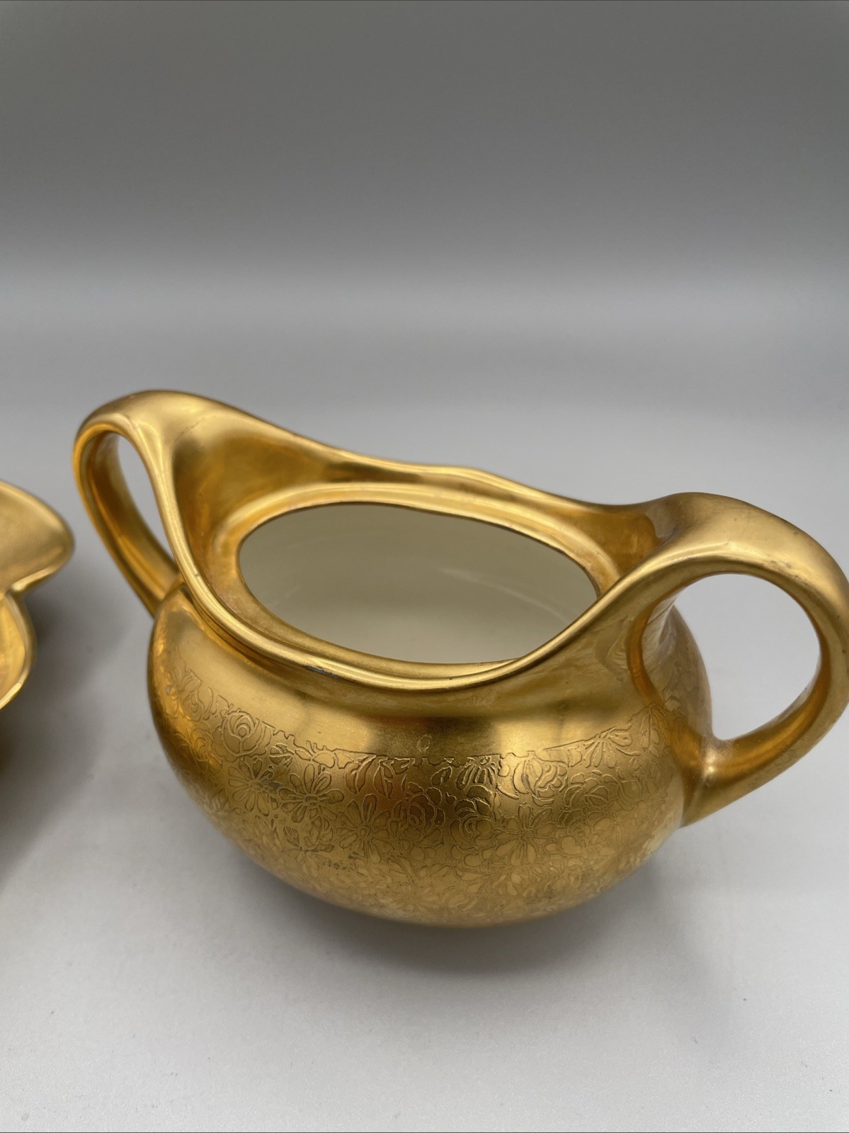Gilded porcelain creamer and saucer set, from Pickard China.