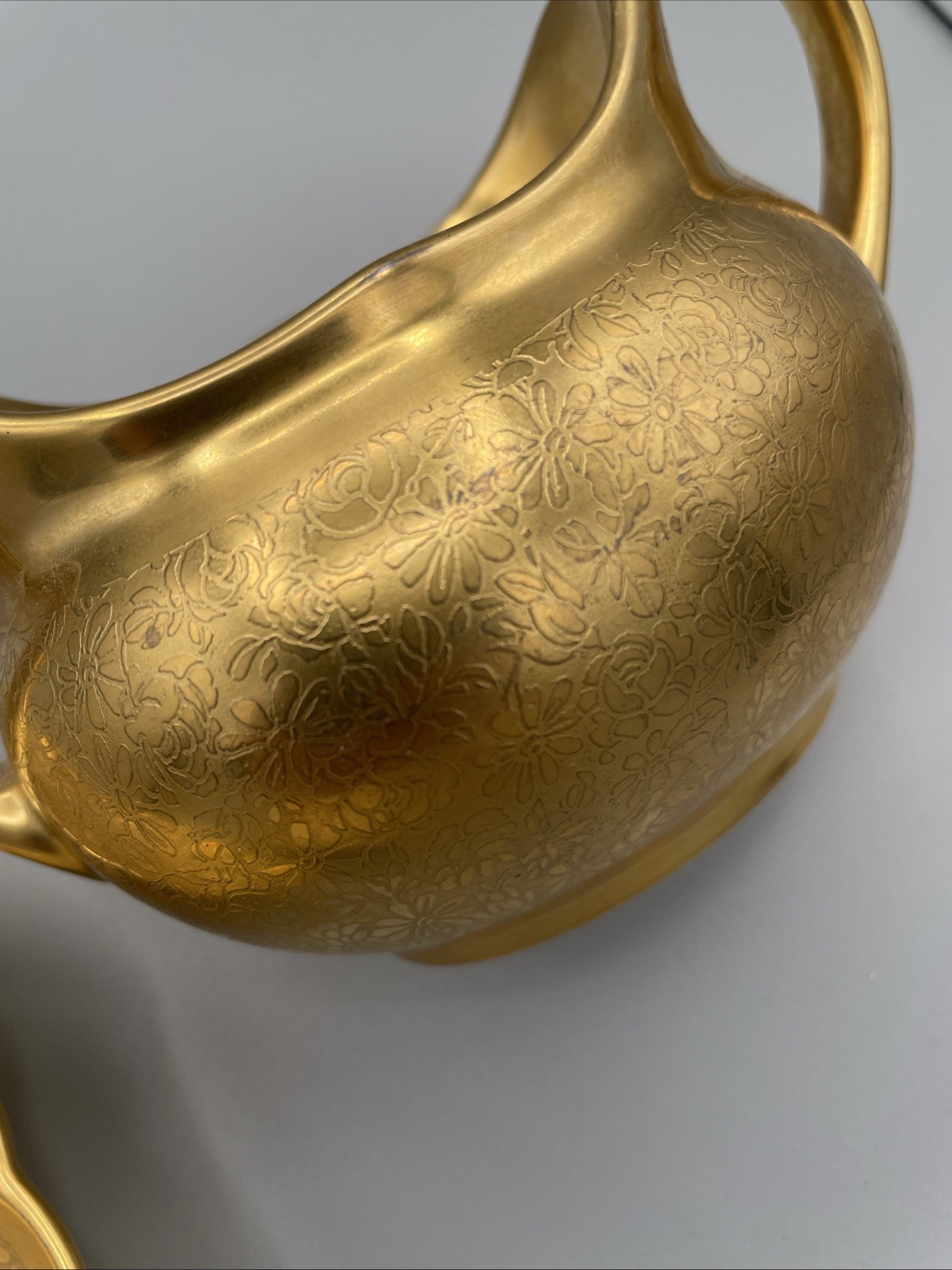 Gilded porcelain creamer and saucer set, from Pickard China.